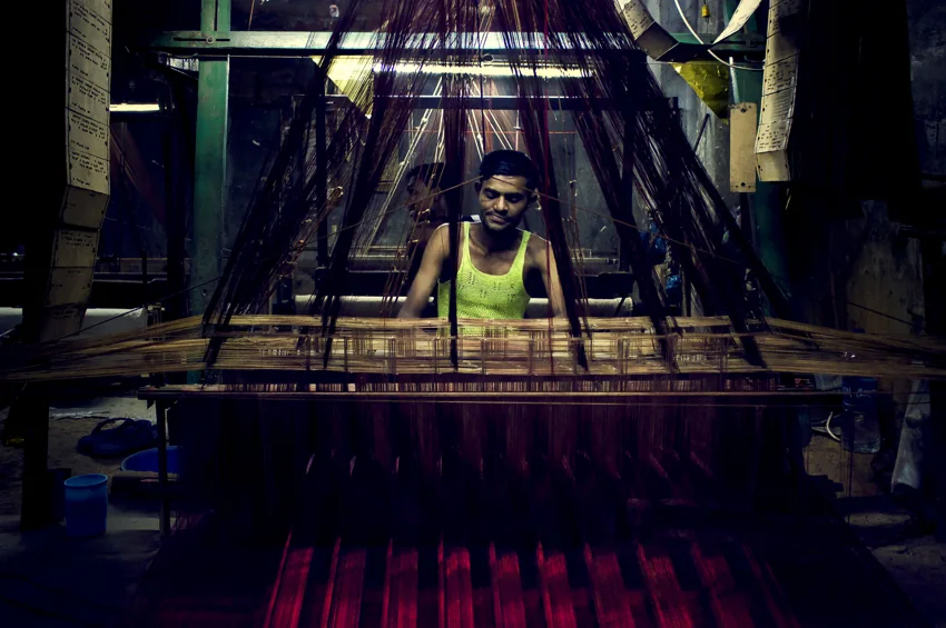 A weaver at work in a dim workshop