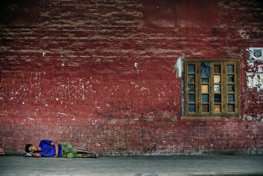 A wide red station wall with a window and a reclining figure.