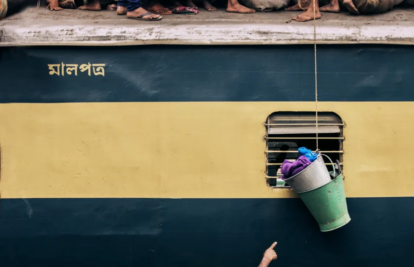 A yellow and green train with an arm reaching toward a hanging bucket.