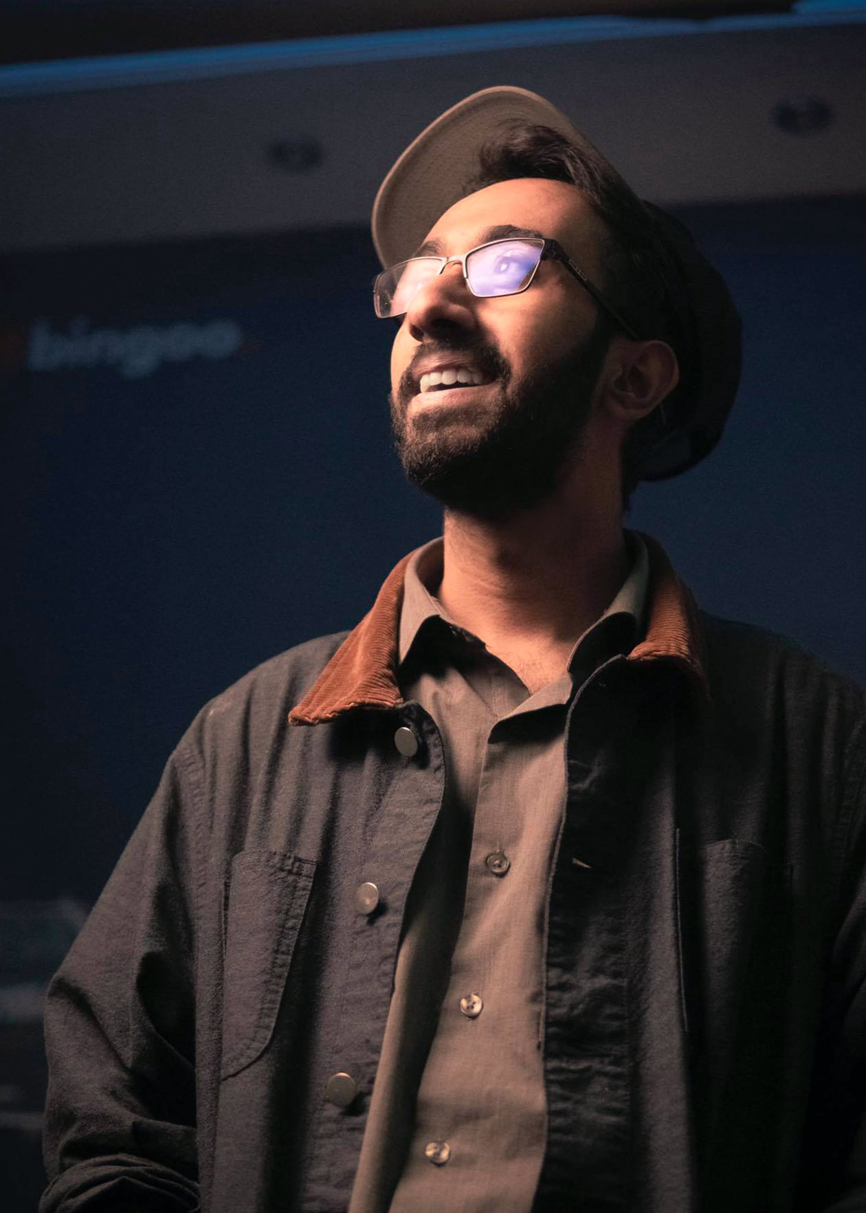 Saif Islam wearing glasses and a hat, looking toward the light